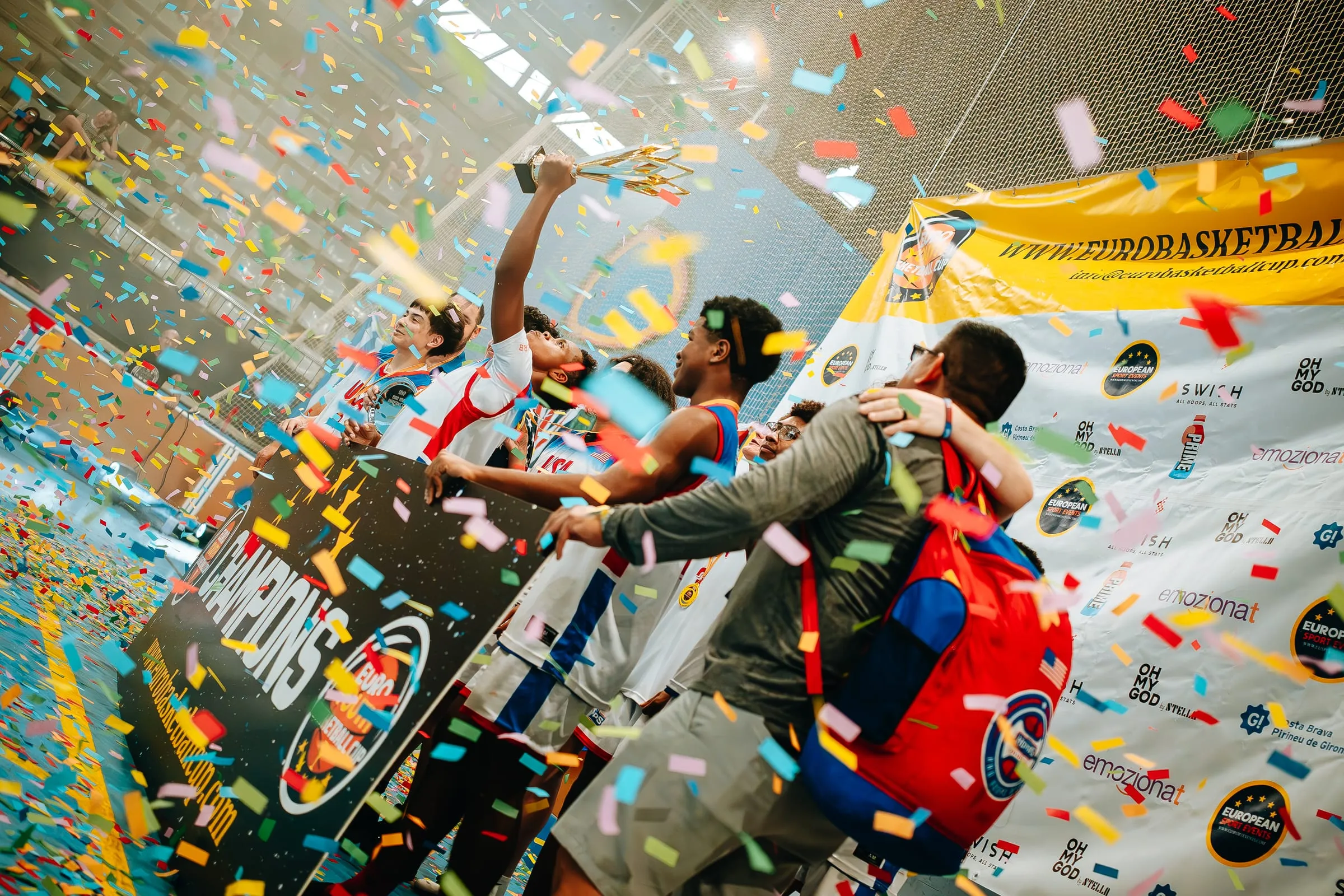 Champions celebrating under falling confetti in front of the tournament board