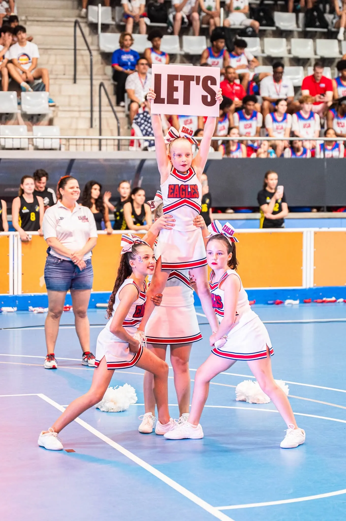 Cheerleaders performing a lift on court while the crowd watches
