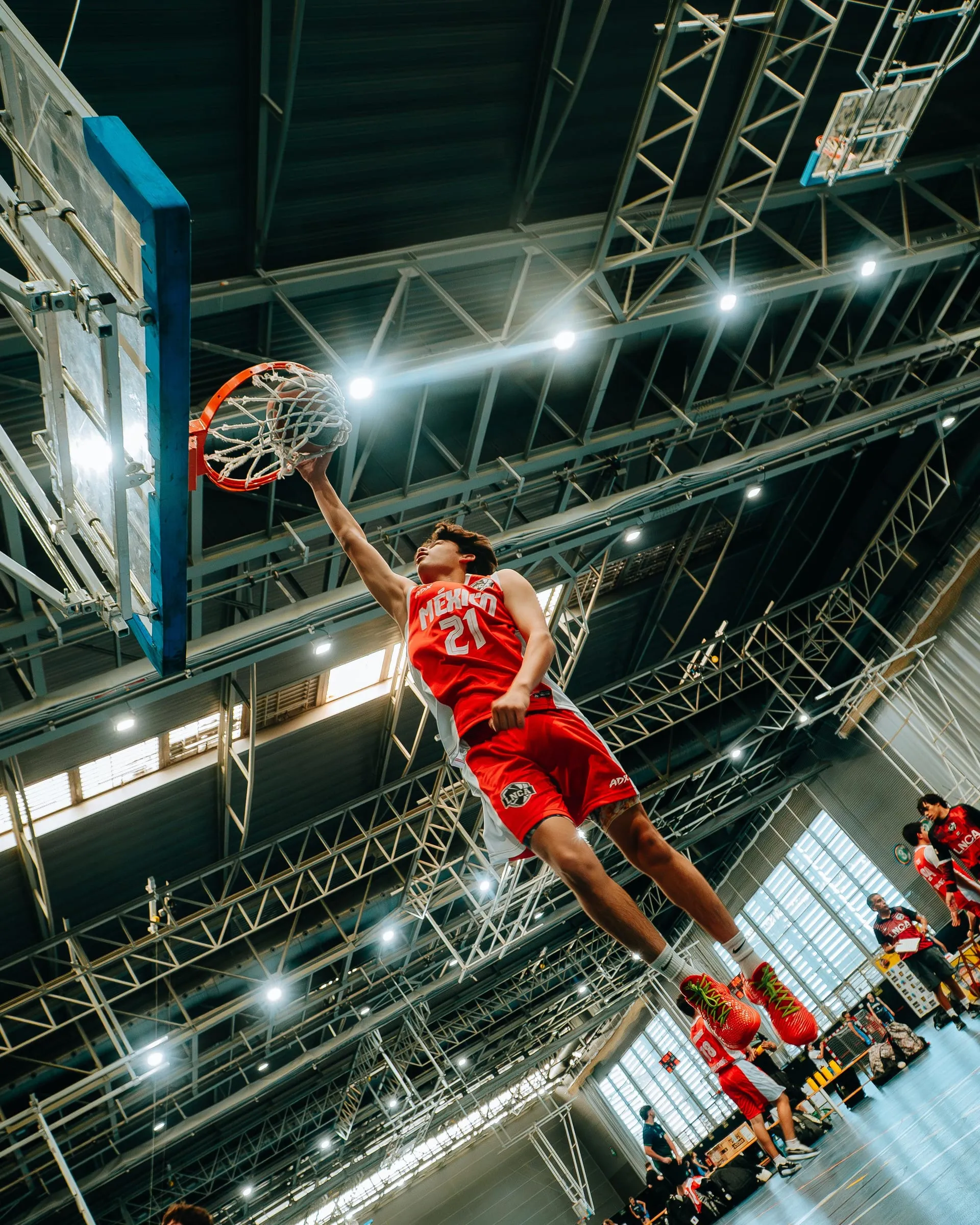 A player hanging from the rim after a dunk, seen from below