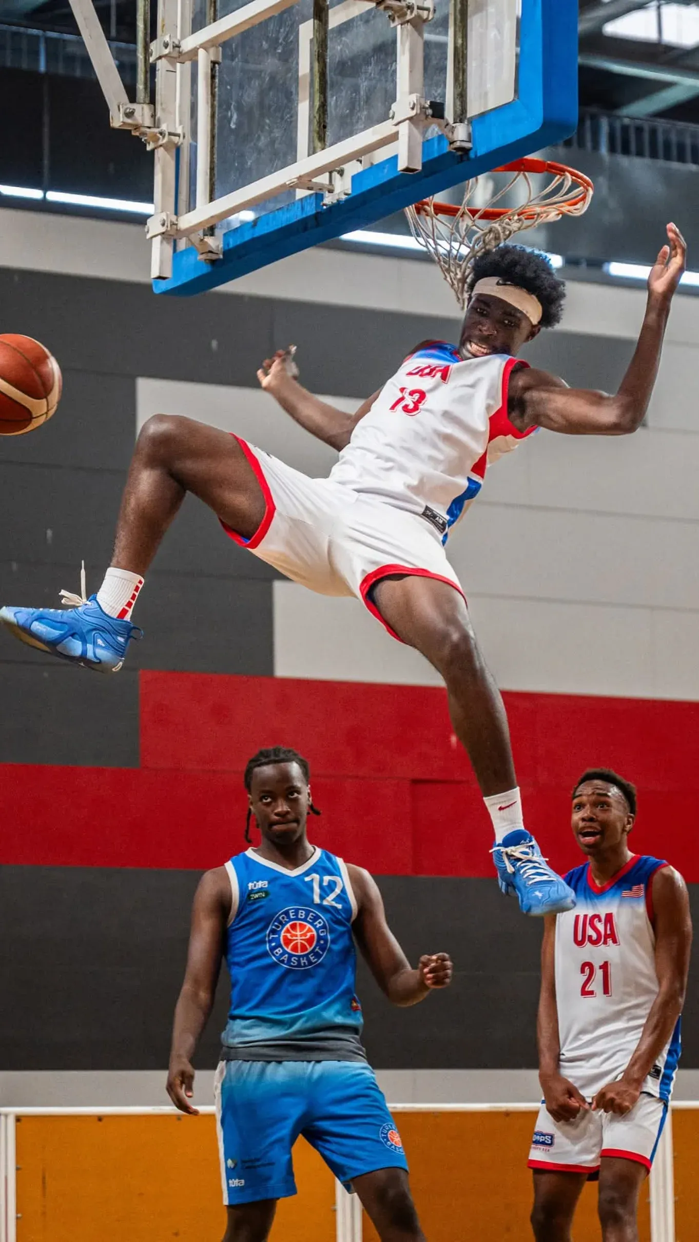 A player leaping to the basket while two others watch from below
